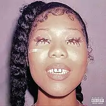 A 2019 photograph of adult dancer and model, Quiana "Qui" Yasuka. She is facing directly at the viewer, with an adhesive bandage below her left eye and jewelry on her incisors.