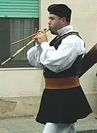 A Sardinian man in traditional clothing playing the launeddas