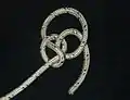 The working end is led around the edge of the underhand knot, and through the loop of the noose