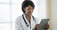 photo of a female doctor facing the reader, holding and looking at a tablet