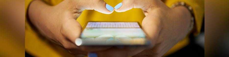 Young adult girl with blue nail polish typing on her smartphone.