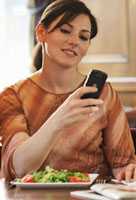 Woman on device while eating.