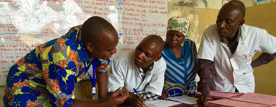 While reviewing maternal and newborn health records with a midwife (center) in Goma, DRC, she had to leave twice to deliver babies (Source: Alaine Knipes, CDC)
