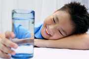 Young boy looking at a glass of water.