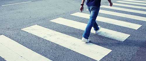 Photo: man in jeans walking across a zebra crossing