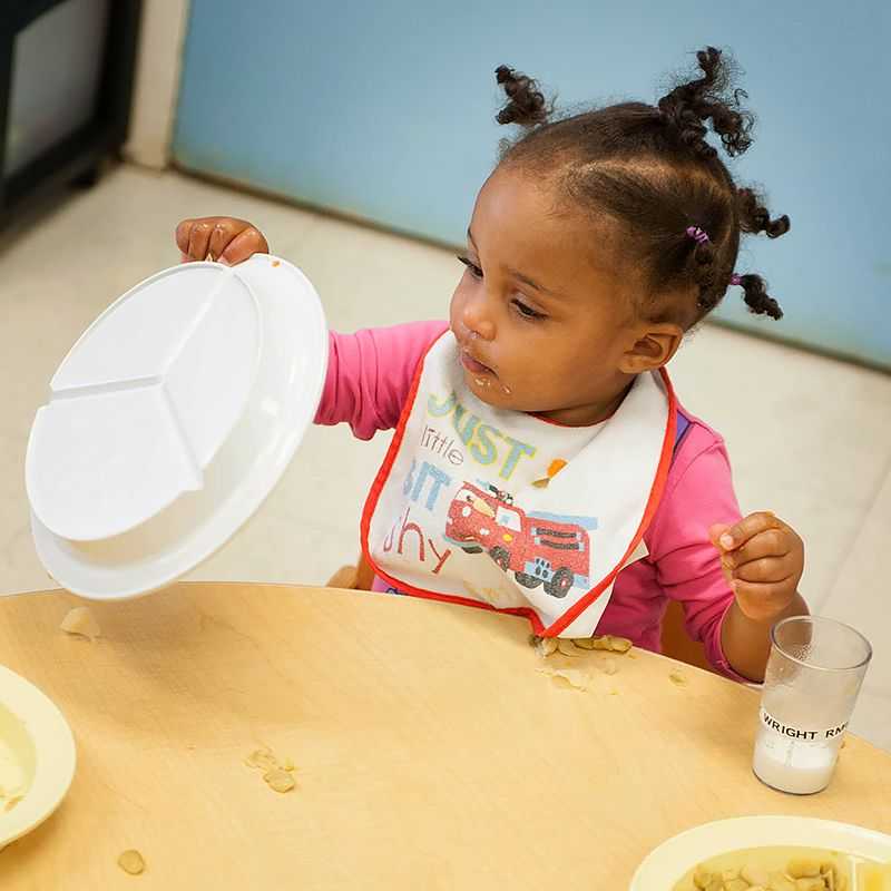 Una niña pequeña da vuelta su plato.