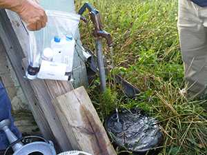 HSB staff gathers water samples from a private well to test for contaminants.