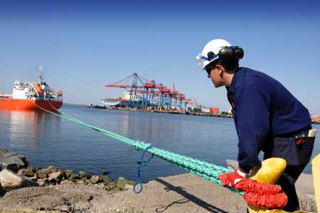 Dock worker secures vessel mooring line to pile.