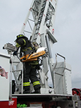 A firefighter is climbing an aerial ladder while in gear.