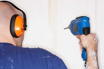Image showing a construction worker using a drill and wearing hearing protection