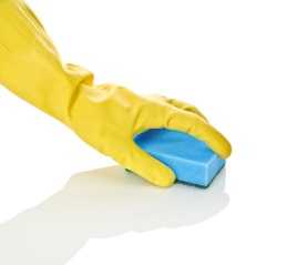 Gloved hand cleaning surface with a sponge.
